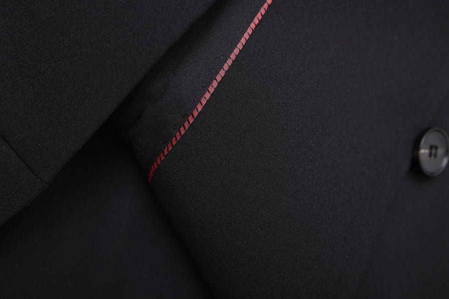 Close-up of the KIKI and JOJO Slim-Fit Black Kids Suit Jacket (3-14 Years), made from wrinkle-free fabric, with a subtle red stitched accent and a single black button on the sleeve.