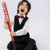 A boy wears a KIKI and JOJO Kids Dress Shirt – White Long Sleeve (Classic Fit), sitting on the floor, smiling with mouth open, holding a red "Supreme" baseball bat against a plain white background.