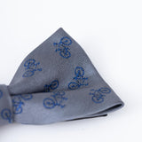 The KIKI and JOJO Kids Bow Tie – Light Gray Bicycle is a pre-tied, adjustable satin bow tie featuring a charming repeating blue bicycle pattern for stylish kids' outfits.