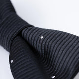 Close-up of the KIKI and JOJO Kids Bow Tie – Black with White Dots, a pre-tied satin bow tie with adjustable fit, set against a plain light background.