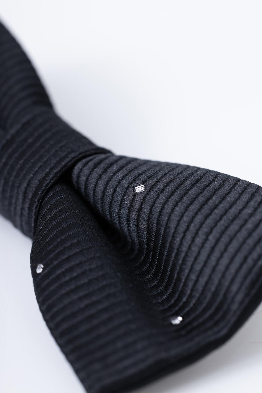 Close-up of the KIKI and JOJO Kids Bow Tie – Black with White Dots, a pre-tied satin bow tie with adjustable fit, set against a plain light background.