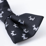 The KIKI and JOJO Kids Bow Tie – Black Puppy is a pre-tied, adjustable satin bow tie in classic black with small white embroidered dogs, offering easy and stylish wear for children.