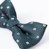 Close-up of the KIKI and JOJO Kids Bow Tie – Green – Pre-Tied Satin, adjustable for comfort, featuring small pink, white, and blue florals on premium fabric against a plain white background.
