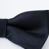 Close-up of the KIKI and JOJO Kids Bow Tie – Black – Pre-Tied Satin with adjustable fit, featuring a rich texture. Perfect accessory for kids dress shirts or tailored suits, shown against a light background.