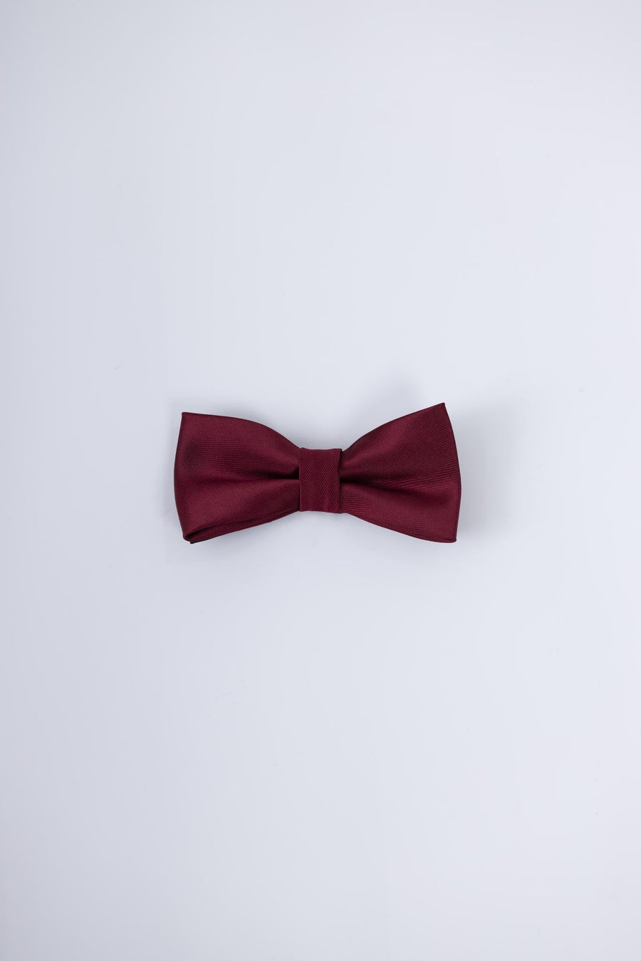 The KIKI and JOJO Kids Bow Tie – Pre-Tied Burgundy Satin – Adjustable is shown against a light gray background, making it a stylish choice for any special occasion.