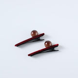 Set of 2 Girls Pearl Hair Clips by KIKI and JOJO, featuring black handcrafted clips with burgundy velvet trim and a round brown bead, displayed on a light gray background.