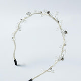 The Beaded Flower Girl Headband – Gold Wire-Wrapped by KIKI and JOJO features gold twisted wire with clear and silver beaded flowers, black tips on each end, and is displayed on a plain light background.