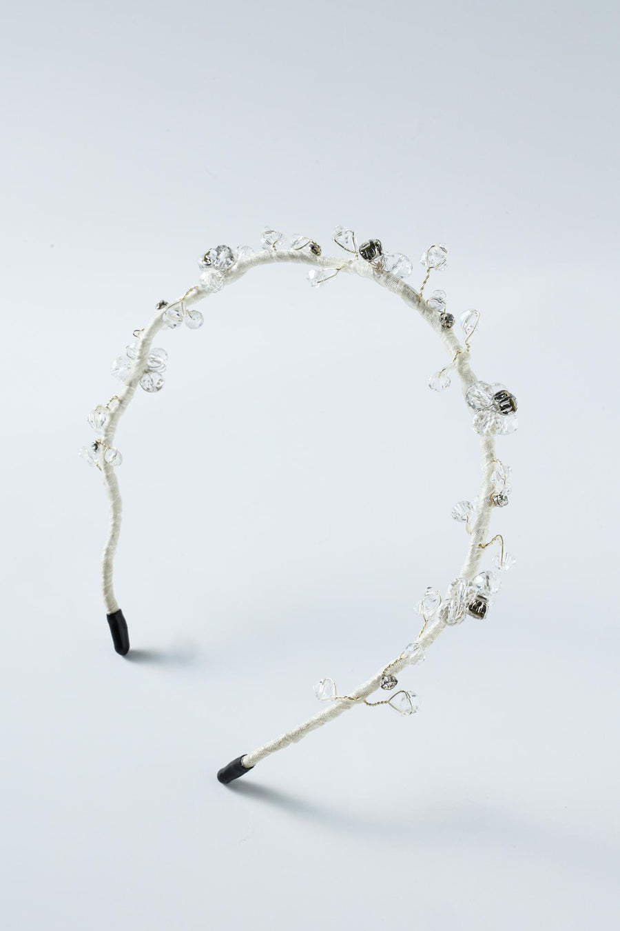 The Beaded Flower Girl Headband – Gold Wire-Wrapped by KIKI and JOJO features gold twisted wire with clear and silver beaded flowers, black tips on each end, and is displayed on a plain light background.