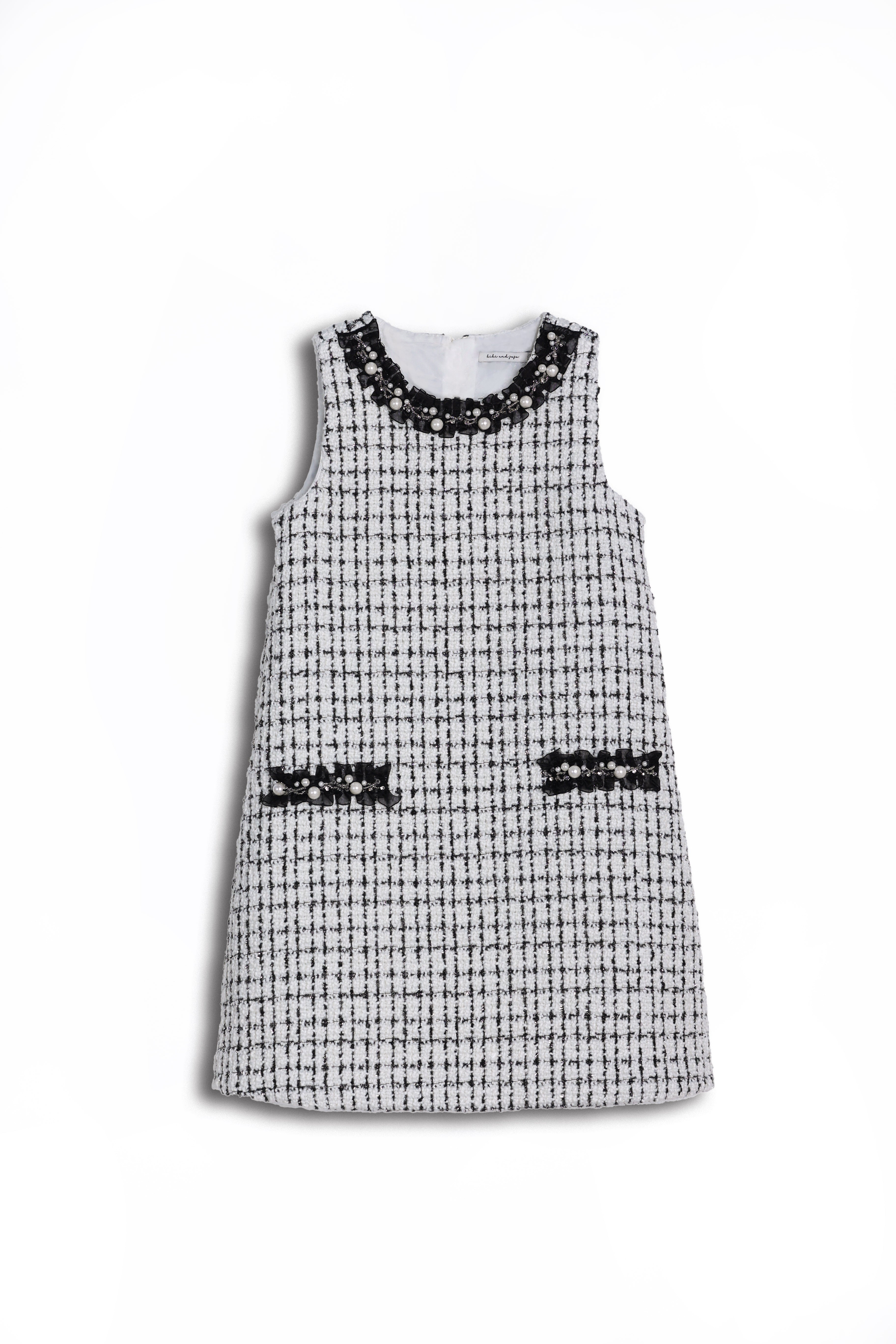 KIKI and JOJO’s Girls Tweed Dress in black & white checkered pearl features a sleeveless design, two front pockets, and a pearl-adorned neckline—ideal for special occasions, shown on a white background.
