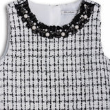 The KIKI and JOJO Girls Tweed Dress – Black & White Checkered Pearl features a sleeveless design, round neckline adorned with pearls and beads, and a classic check pattern—ideal for special occasions.