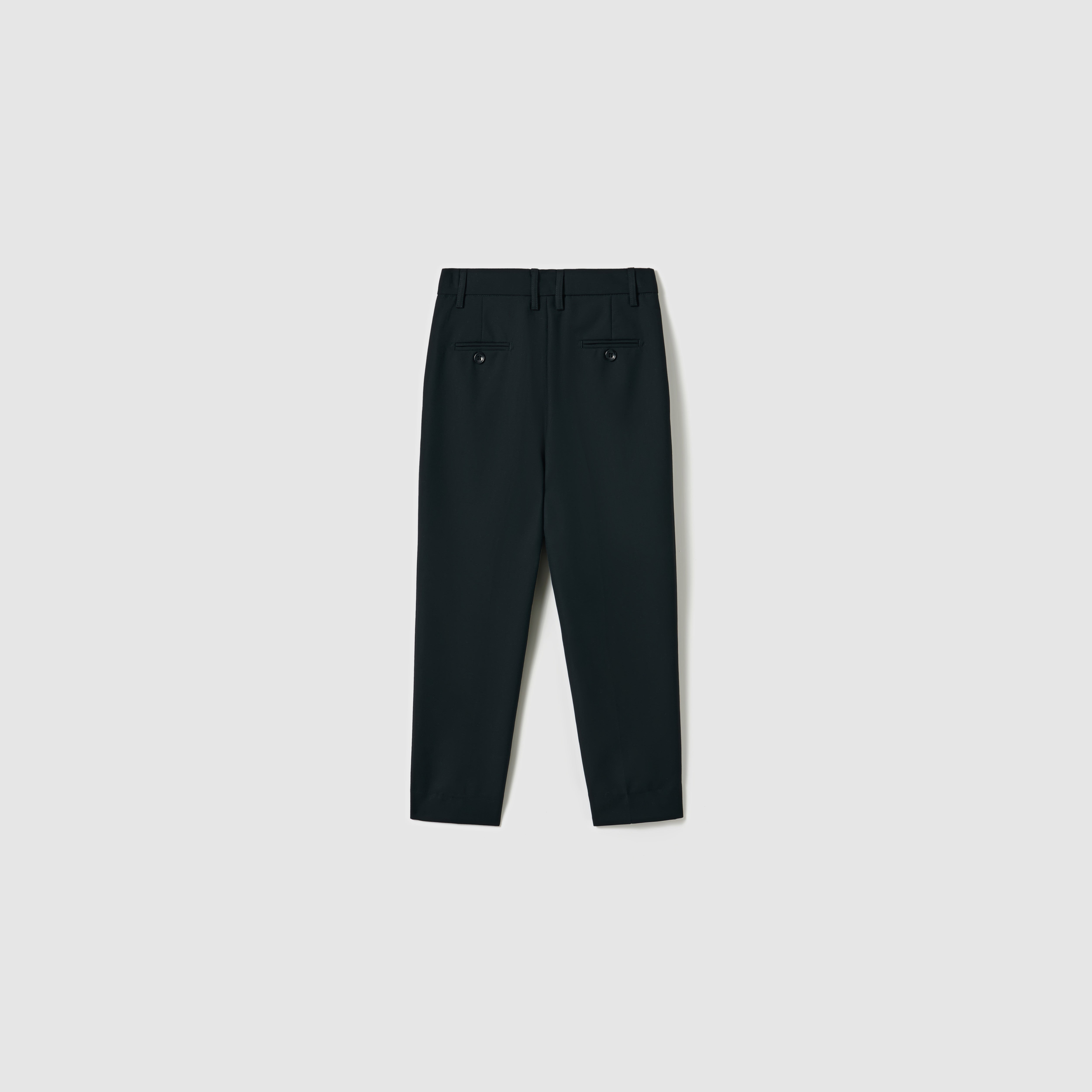 KIKI and JOJO’s Noir Bloom Suit Pants for boys feature a straight-leg cut, two buttoned back pockets, and belt loops—ideal formal black trousers shown from the rear against a plain light background.