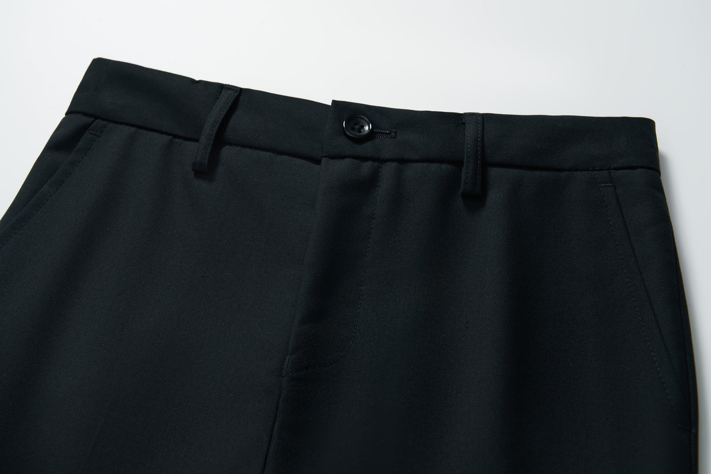 Close-up of the waistband and upper section of KIKI and JOJO's Noir Bloom Suit Pants for boys, featuring belt loops, button closure, and side pockets on a white background—ideal for formal occasions.