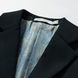 A close-up of the Noir Bloom Suit Jacket by KIKI and JOJO, a boys' black jacket with a classic notched lapel, blue paisley-patterned lining, and a visible brand label sewn into the collar area.