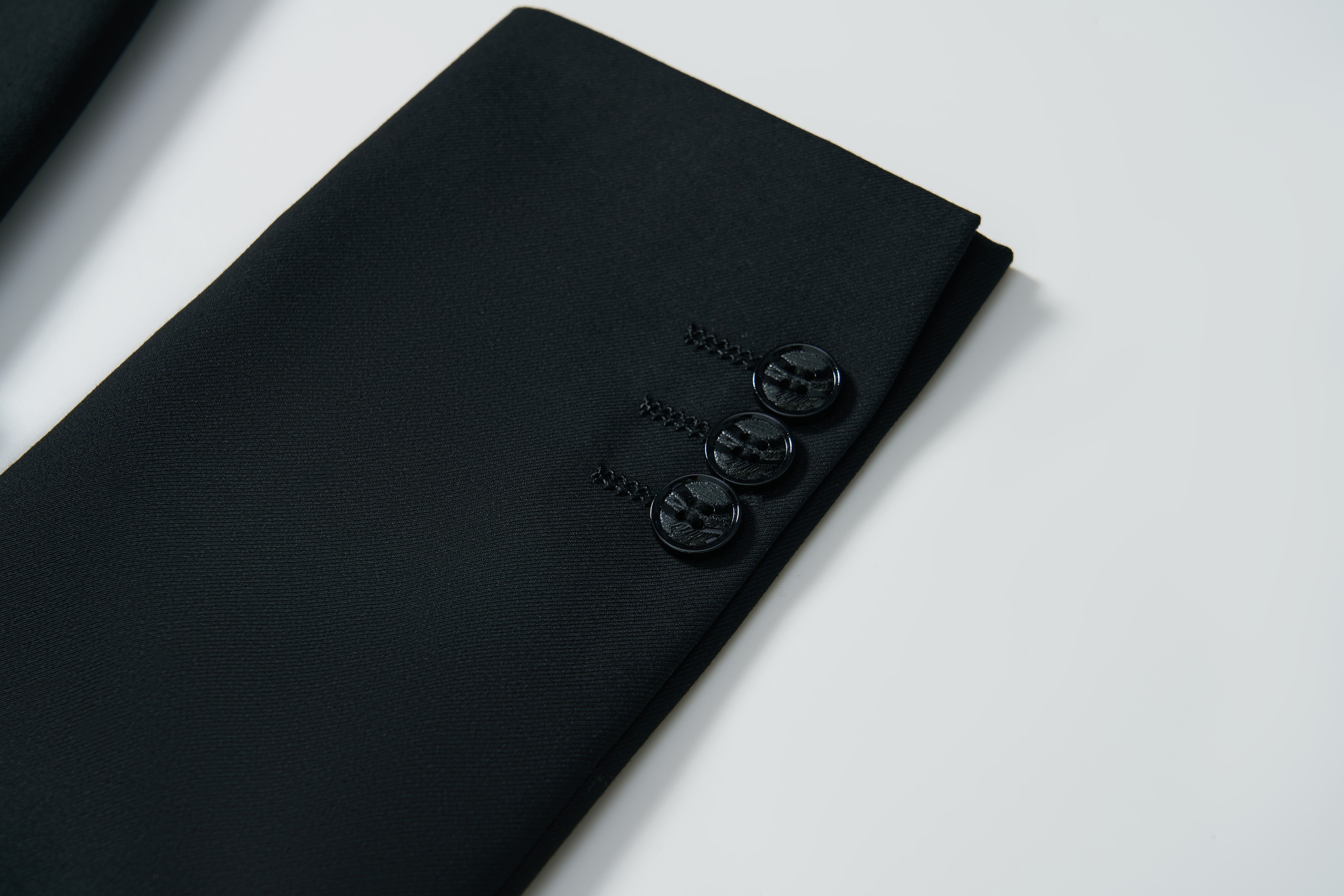 Close-up of the sleeve of the KIKI and JOJO Noir Bloom Suit Jacket for boys, showing three black buttons against a white background.