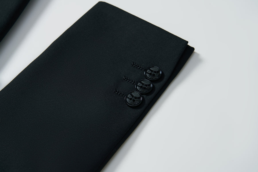 Close-up of the sleeve of the KIKI and JOJO Noir Bloom Suit Jacket for boys, showing three black buttons against a white background.