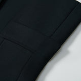 Close-up of the Noir Bloom Suit Jacket by KIKI and JOJO, featuring a neatly folded black sleeve with classic notched lapel, visible button, and seam detail displayed on a white surface.