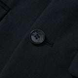 Close-up of the KIKI and JOJO Noir Bloom Suit Jacket shows a fastened button on black fabric, classic notched lapel, fine stitching, and two pocket flaps on each side.