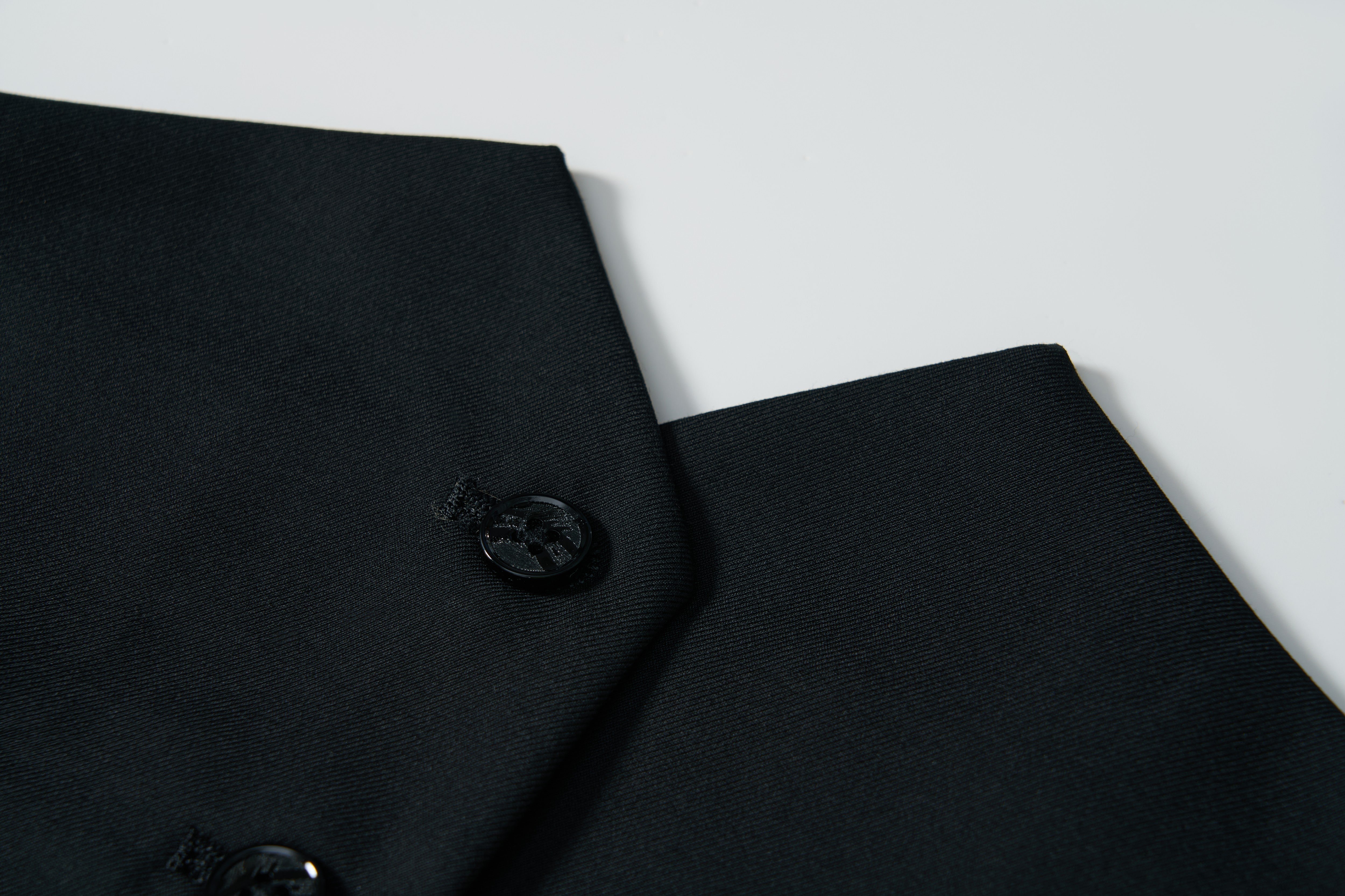 Close-up of the Noir Bloom Suit Vest by KIKI and JOJO—a sleek black vest with a single button, set against a plain white background. This classic piece is perfect for elevating any formal wardrobe.