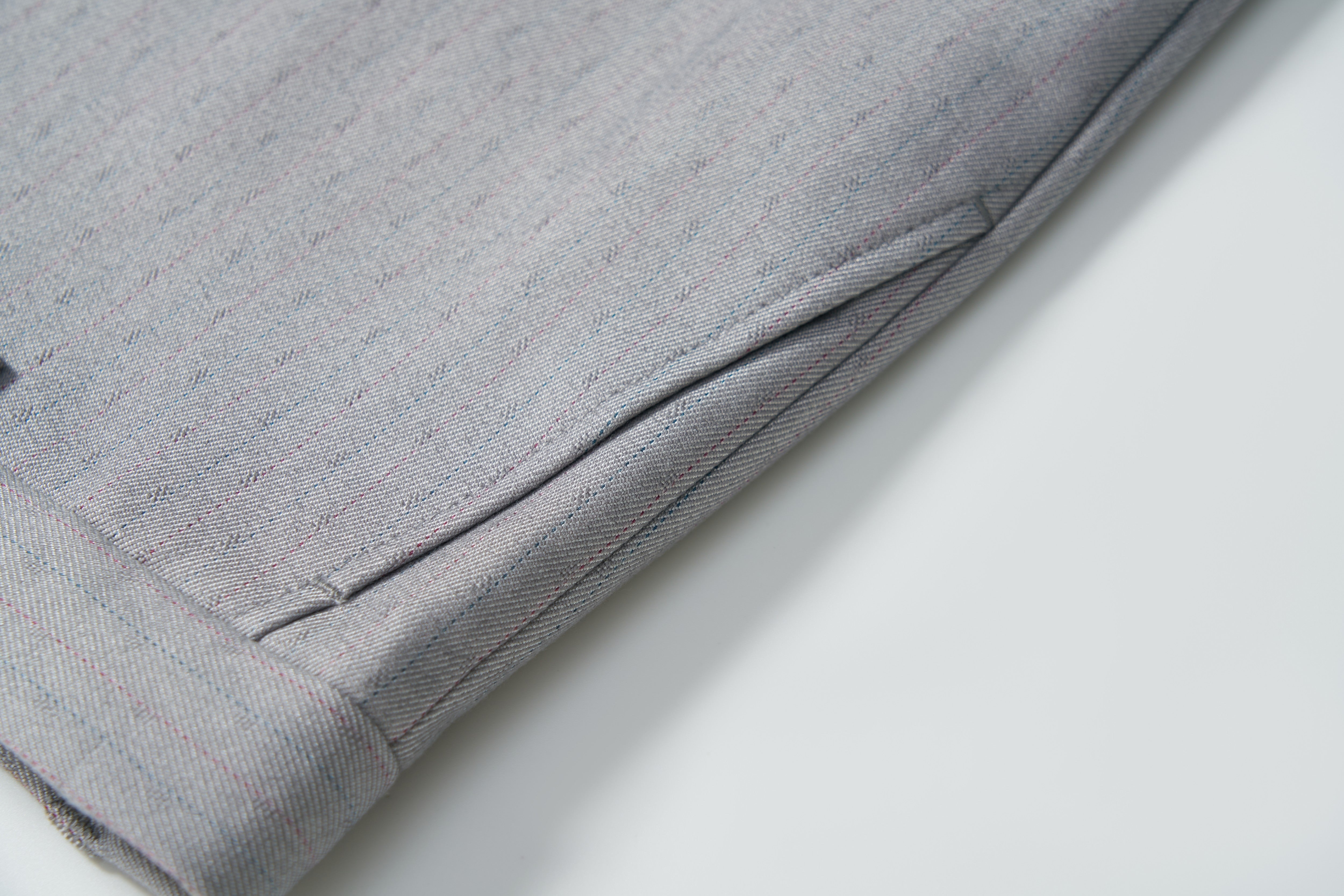 Close-up of KIKI and JOJO Silver Bloom Suit Pants for boys, featuring a gray pinstripe design, cuffed hem, adjustable waistband, and side pocket, laid flat on a white surface.
