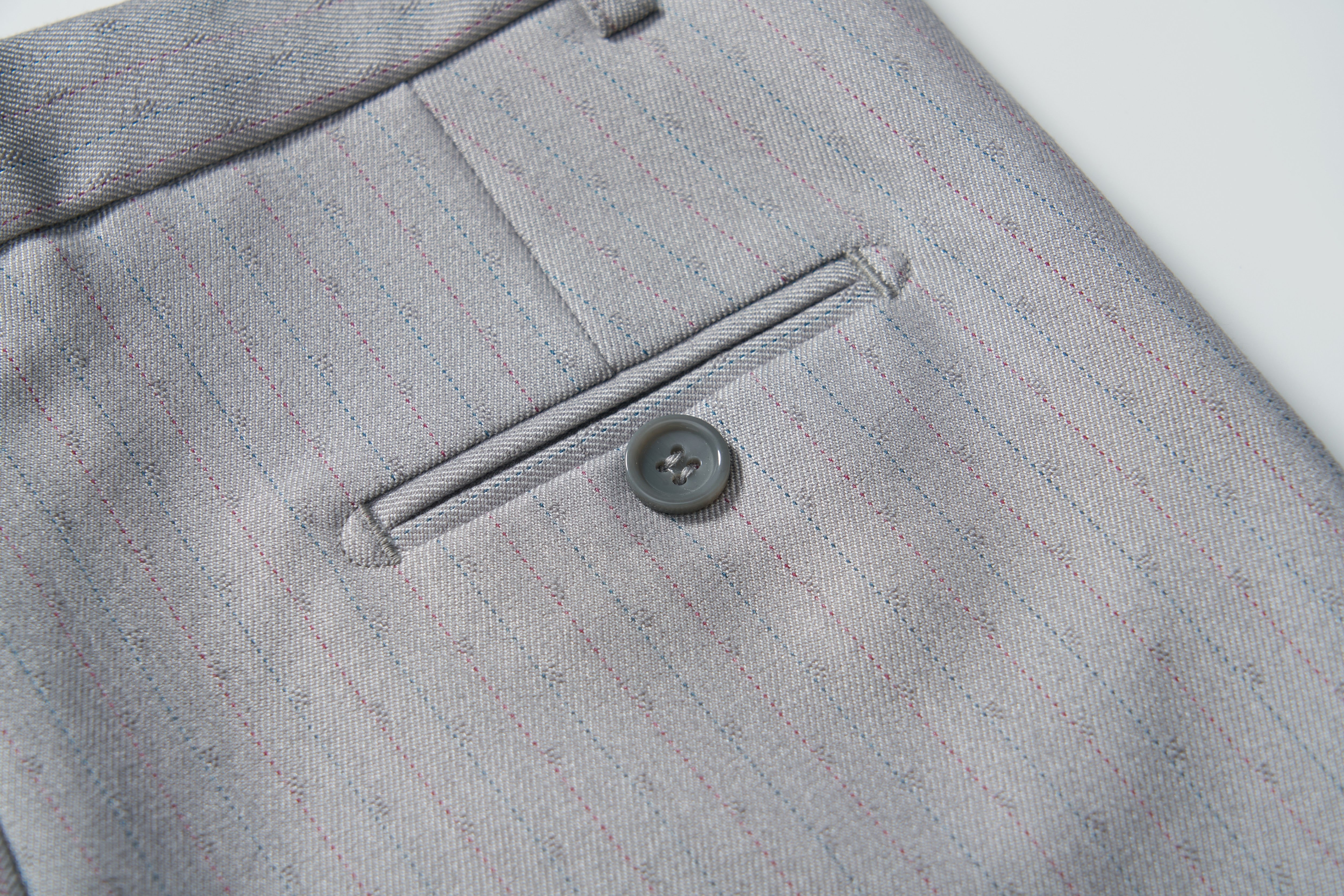 Close-up of the back pocket of KIKI and JOJO's Silver Bloom Suit Pants, showing a single-button horizontal welt pocket and an adjustable waistband for comfort.