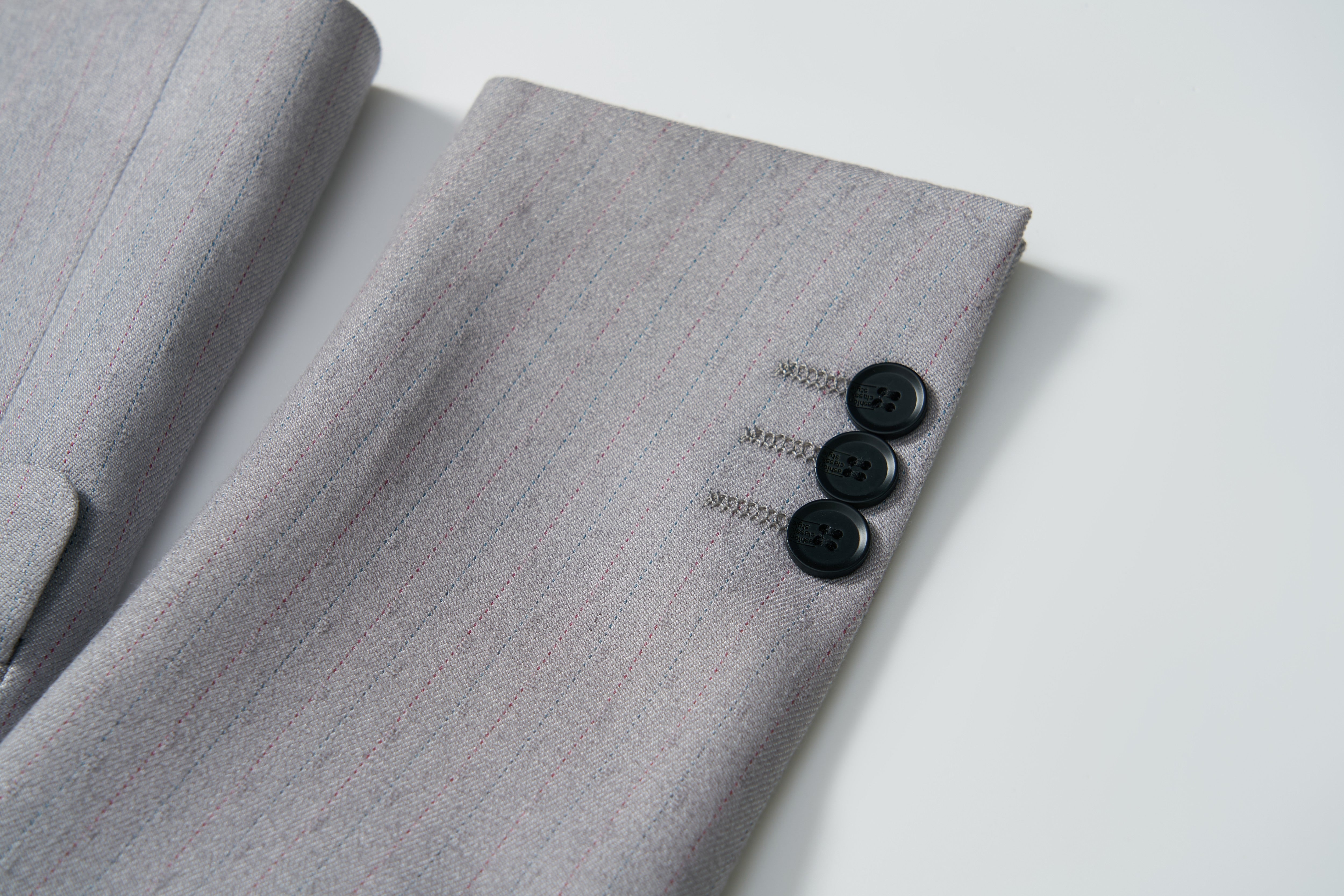 Close-up of the Silver Bloom Suit Jacket by KIKI and JOJO, showcasing its light gray stripes and three black cuff buttons—ideal for formal boys' attire.