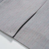 Close-up of the Silver Bloom Suit Jacket by KIKI and JOJO, showing its light gray pinstripe fabric with a seam and pleat, displayed on a white surface.
