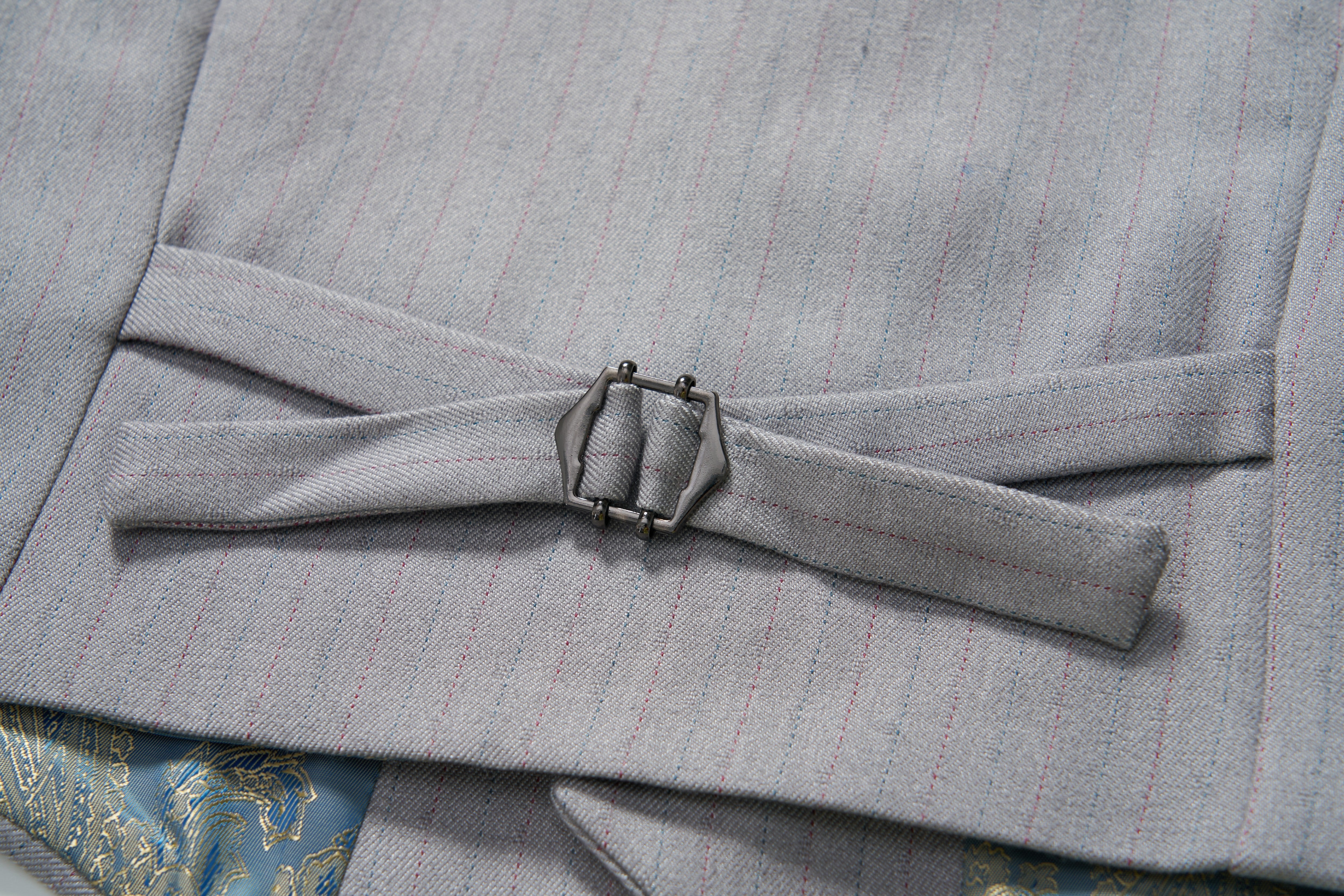 Close-up of an adjustable side strap with a metal buckle on the KIKI and JOJO Silver Bloom Suit Vest, showing part of patterned fabric underneath.