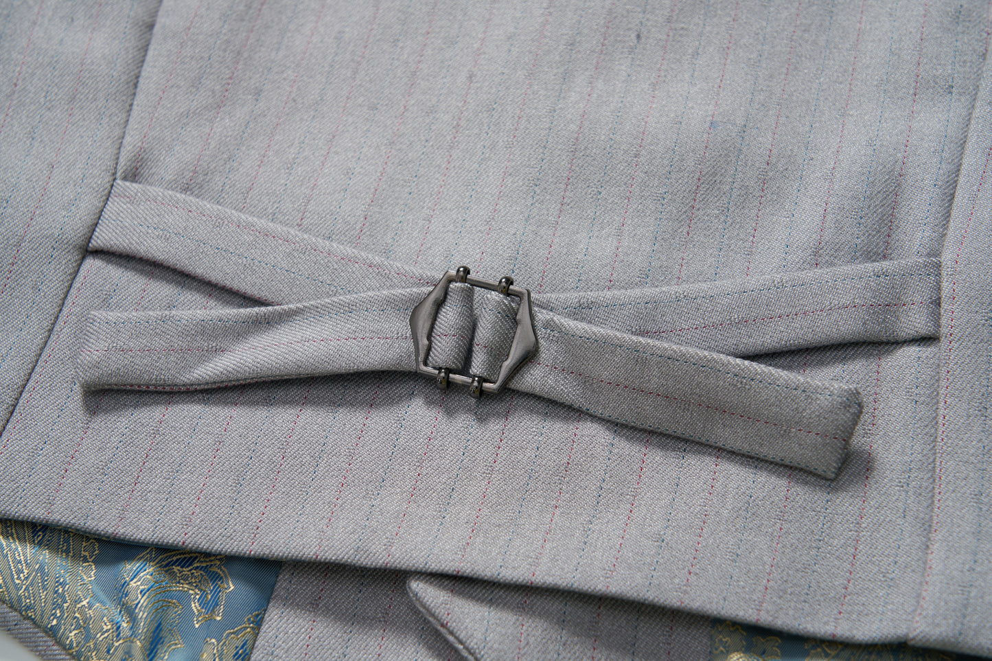 Close-up of an adjustable side strap with a metal buckle on the KIKI and JOJO Silver Bloom Suit Vest, showing part of patterned fabric underneath.