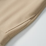 Close-up of the hem and side pocket of KIKI and JOJO Savoy Dune Suit Pants in beige, featuring detailed stitching, fabric texture, and an adjustable waistband against a white background.