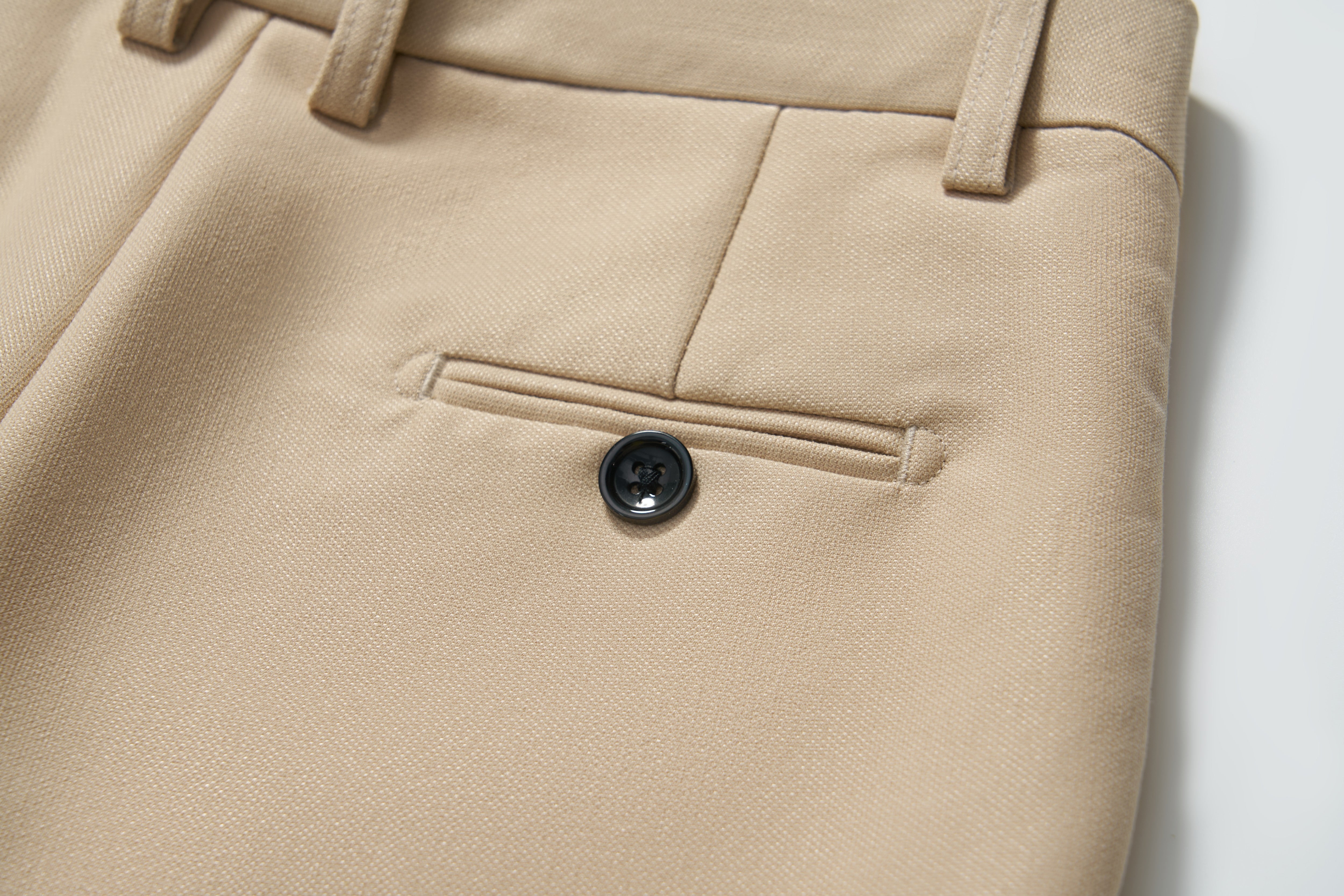 Close-up of KIKI and JOJO's Savoy Dune Suit Pants, showing a back welt pocket with a single black button, belt loops, and an adjustable waistband for a tailored fit.
