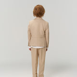 A person with short, light brown hair in a beige suit faces away from the camera against a plain background, showcasing KIKI and JOJO’s Savoy Dune Suit Pants for boys, featuring an adjustable waistband for comfort.