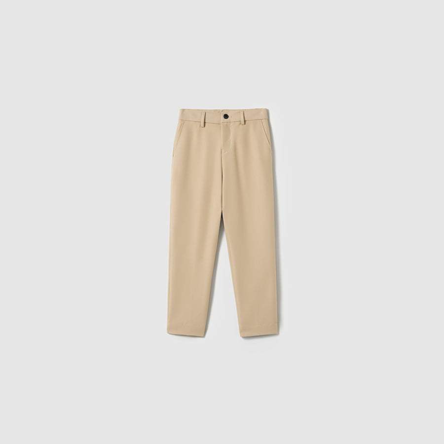 The Savoy Dune Suit Pants by KIKI and JOJO are beige boys' straight-leg dress pants with belt loops, side pockets, an adjustable waistband, and a front button closure, shown on a plain light gray background.