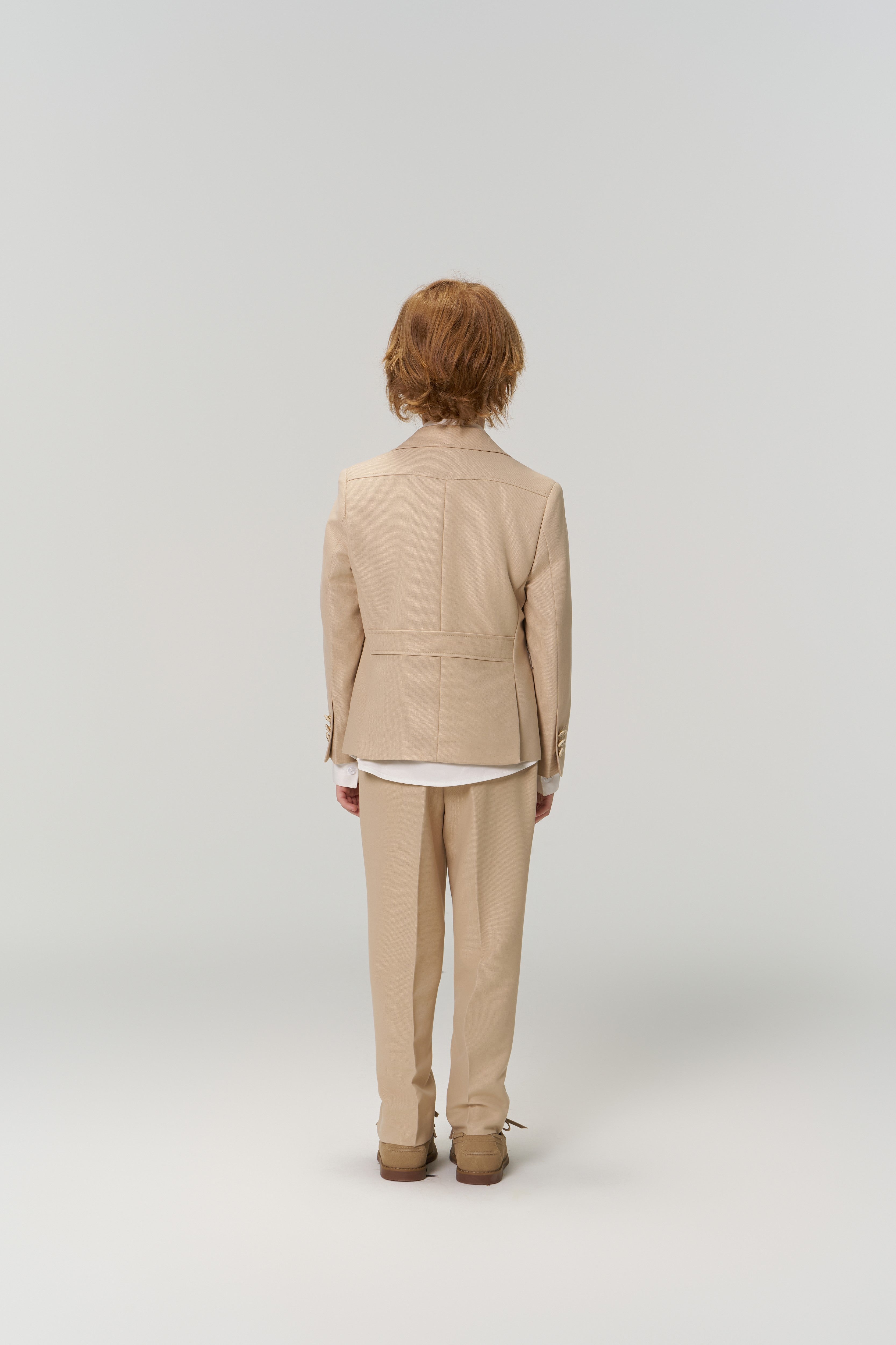 A person with short, light brown hair faces away from the camera, modeling the KIKI and JOJO Savoy Dune Suit Jacket against a plain, light backdrop.