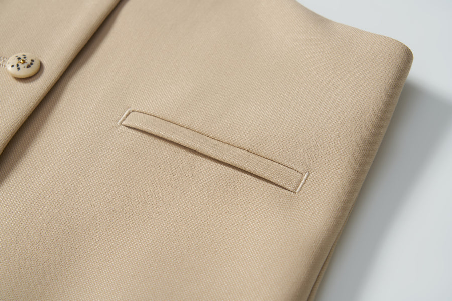 Close-up of the Savoy Dune Suit Vest by KIKI and JOJO, showcasing its smooth, textured fabric with a welt pocket and button—ideal for special occasions.