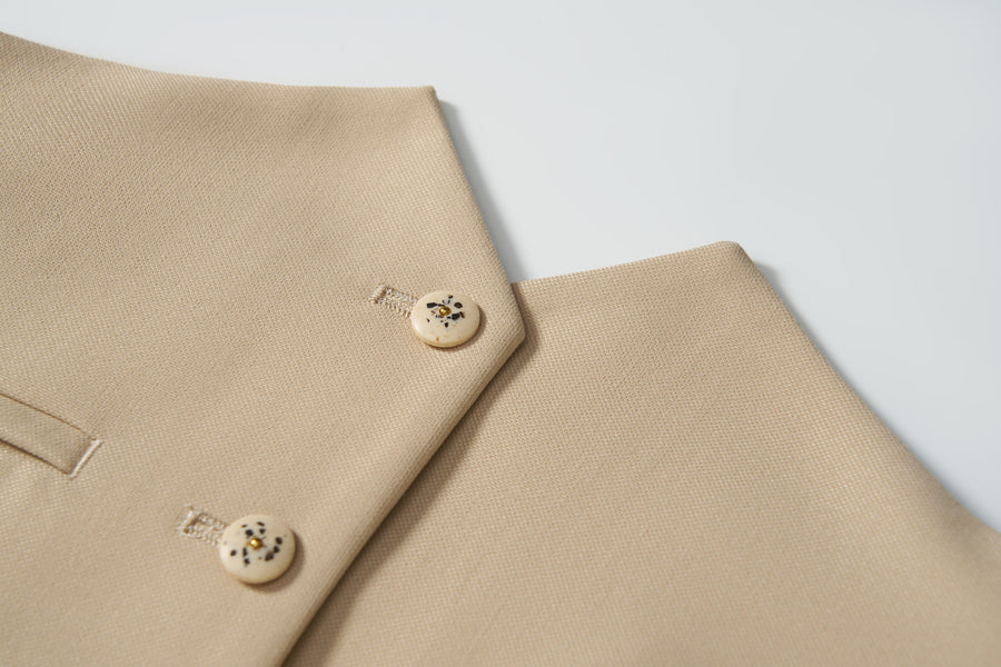 Close-up of a khaki beige blazer with two cream buttons and a welt pocket, ideal for pairing with the KIKI and JOJO Savoy Dune Suit Vest for any special occasion, displayed on a white background.