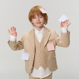 A young child in a beige suit stands with hands raised, covered in various pastel-colored sticky notes on their face, hands, and jacket.