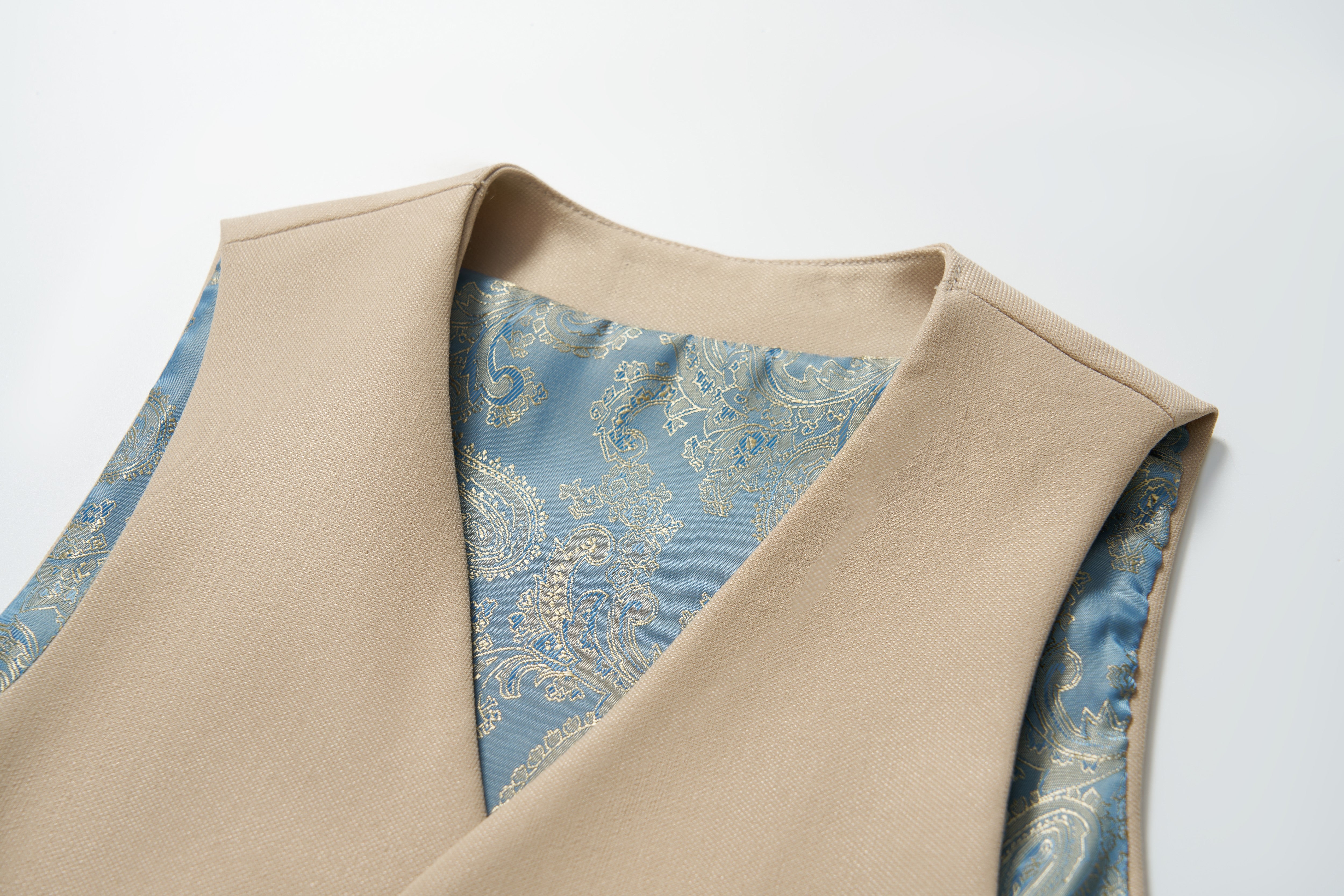A close-up of the KIKI and JOJO Savoy Dune Suit Vest in khaki beige, featuring a blue and silver paisley lining—ideal for boys’ special occasions—shown against a plain white background.