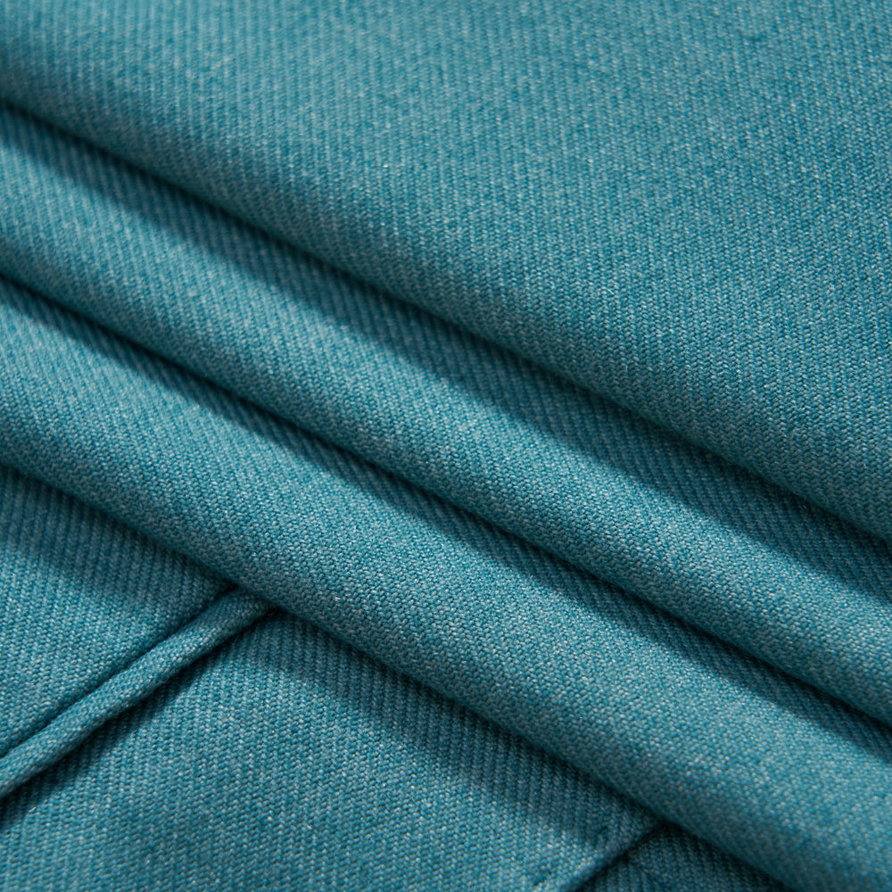 Close-up of teal-colored fabric with neatly folded sections and visible textured weave.