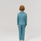 A child with red hair wears the KIKI and JOJO Celeste Whimsy Suit Jacket and white shoes, standing with their back to the camera against a plain light background.
