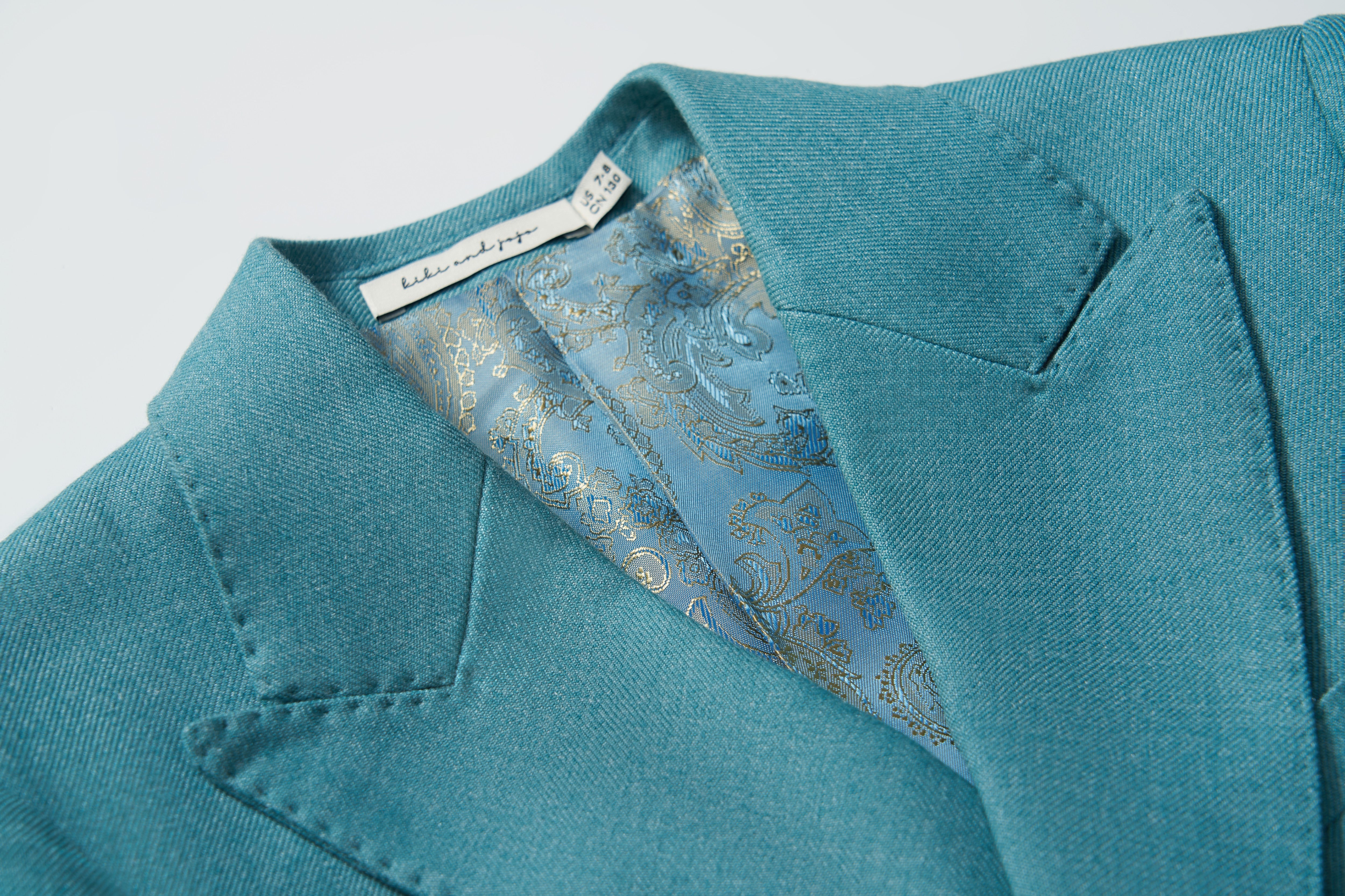 Close-up of the Celeste Whimsy Suit Jacket by KIKI and JOJO in celeste blue, featuring a paisley-patterned blue lining and a visible KIKI and JOJO designer label inside the collar.