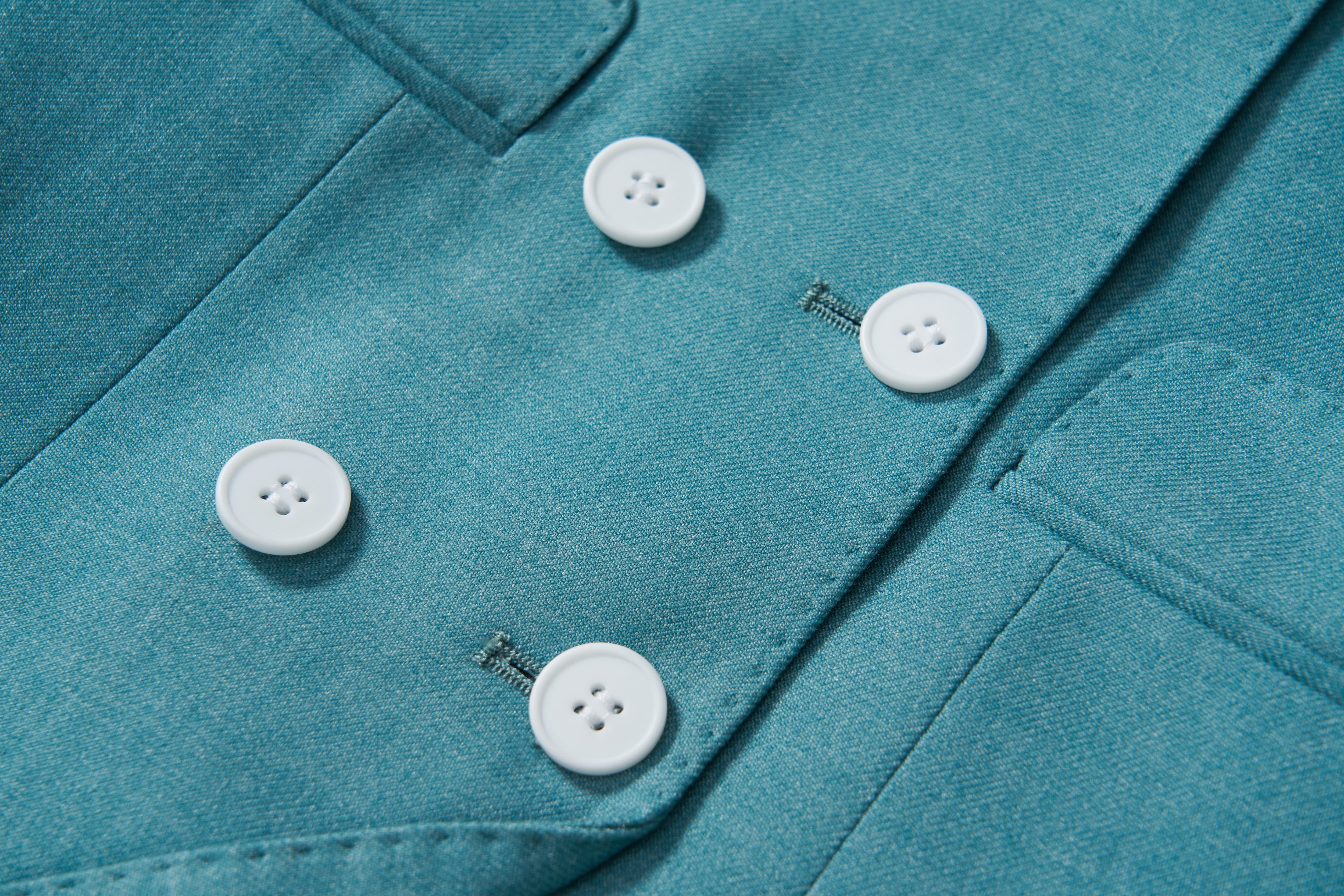 Close-up of the KIKI and JOJO Celeste Whimsy Suit Jacket for boys, shown in celeste blue with three white buttons and two visible pockets.