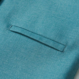 Close-up of the Celeste Whimsy Suit Vest by KIKI and JOJO in peacock blue, featuring a welt pocket and part of a button, ideal for formalwear, set against a light background.