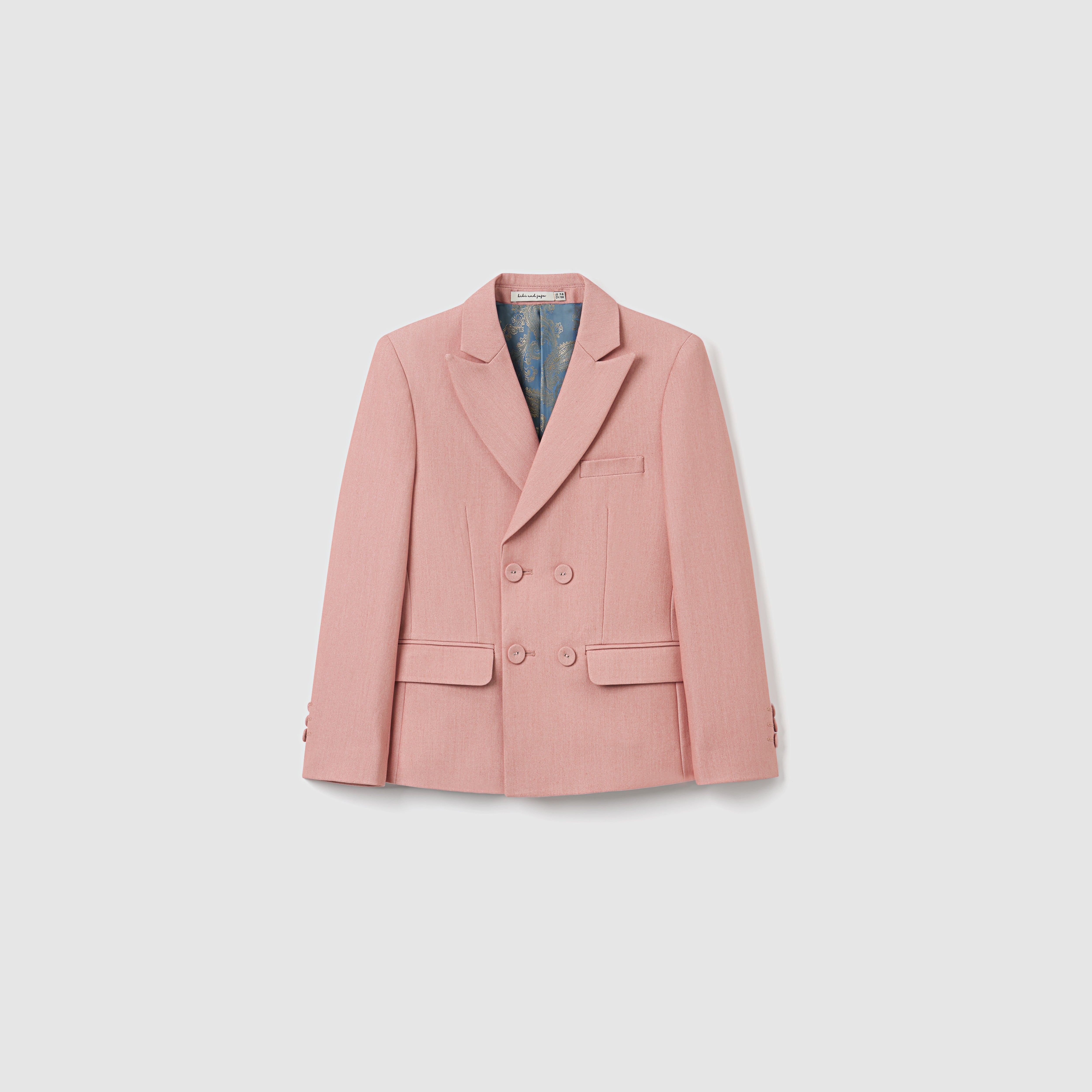 The KIKI and JOJO Blush Reverie Suit Jacket is a blush pink, double-breasted boys blazer with notch lapels, two front flap pockets, and a chest pocket—perfect for special occasions and shown against a plain white background.