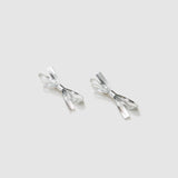 The KIKI and JOJO Girls Silver Bow Hair Clips - Set of 2 feature metallic silver PU leather bows, beautifully displayed on a light gray background—ideal as elegant hair accessories.