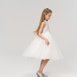 A young girl with long hair wears KIKI and JOJO’s Girls Crystal Garden Barrettes (set of 2), a white sleeveless dress, and silver shoes, standing against a plain light background.