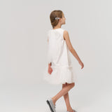 A young girl wearing KIKI and JOJO Girls Crystal Garden Barrettes (set of 2) in her hair, a white dress, and silver shoes walks to the right against a plain white background.