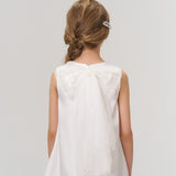 A young girl with light brown hair in a loose braid, styled with KIKI and JOJO Girls Crystal Garden Barrettes (Set of 2), is shown from behind wearing a white dress with a sheer bow and layered tulle skirt.