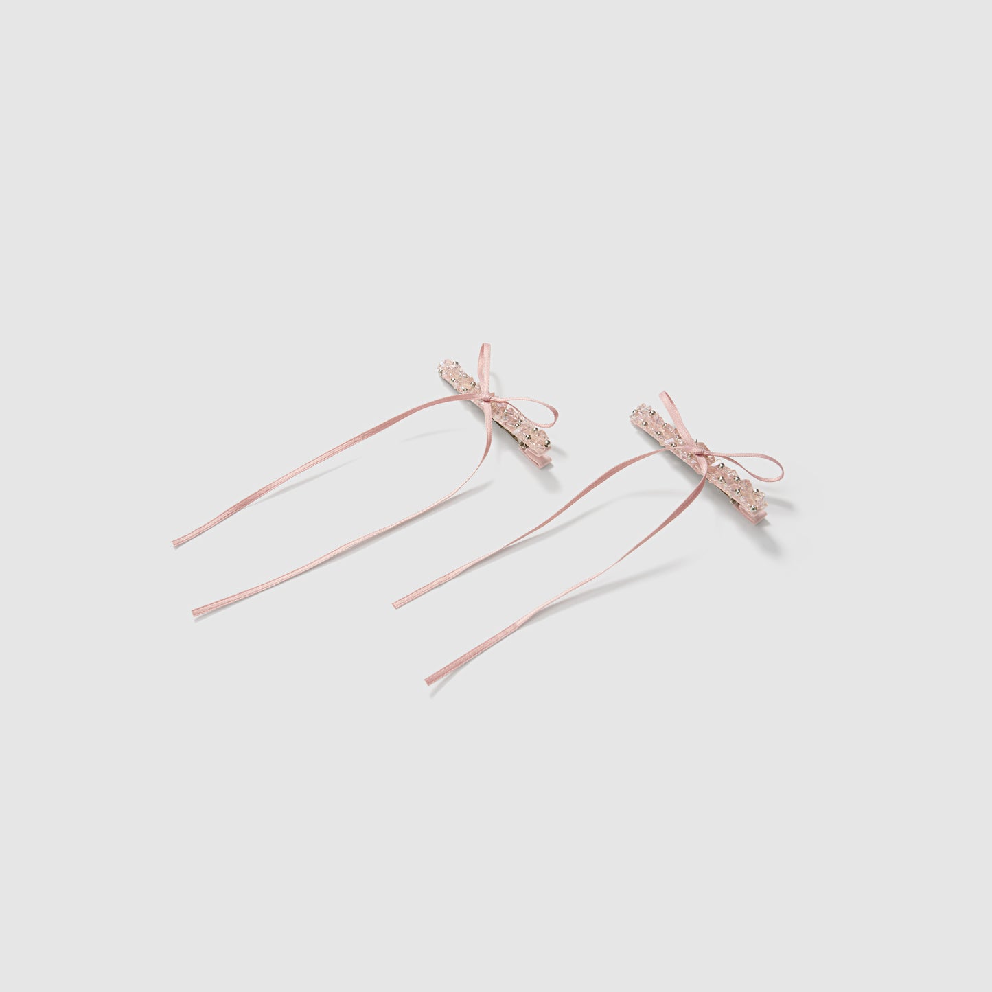 KIKI and JOJO Girls Pink Beaded Bow Hair Clips - Set of 2 features pink satin clips with lace bows, trailing ribbons, and faux pearl accents, displayed on a plain light background.