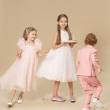 Three children in formalwear stand on a beige background; one girl, wearing a KIKI and JOJO Girls Black Beaded Bow Hair Clip, holds a cake with candles.