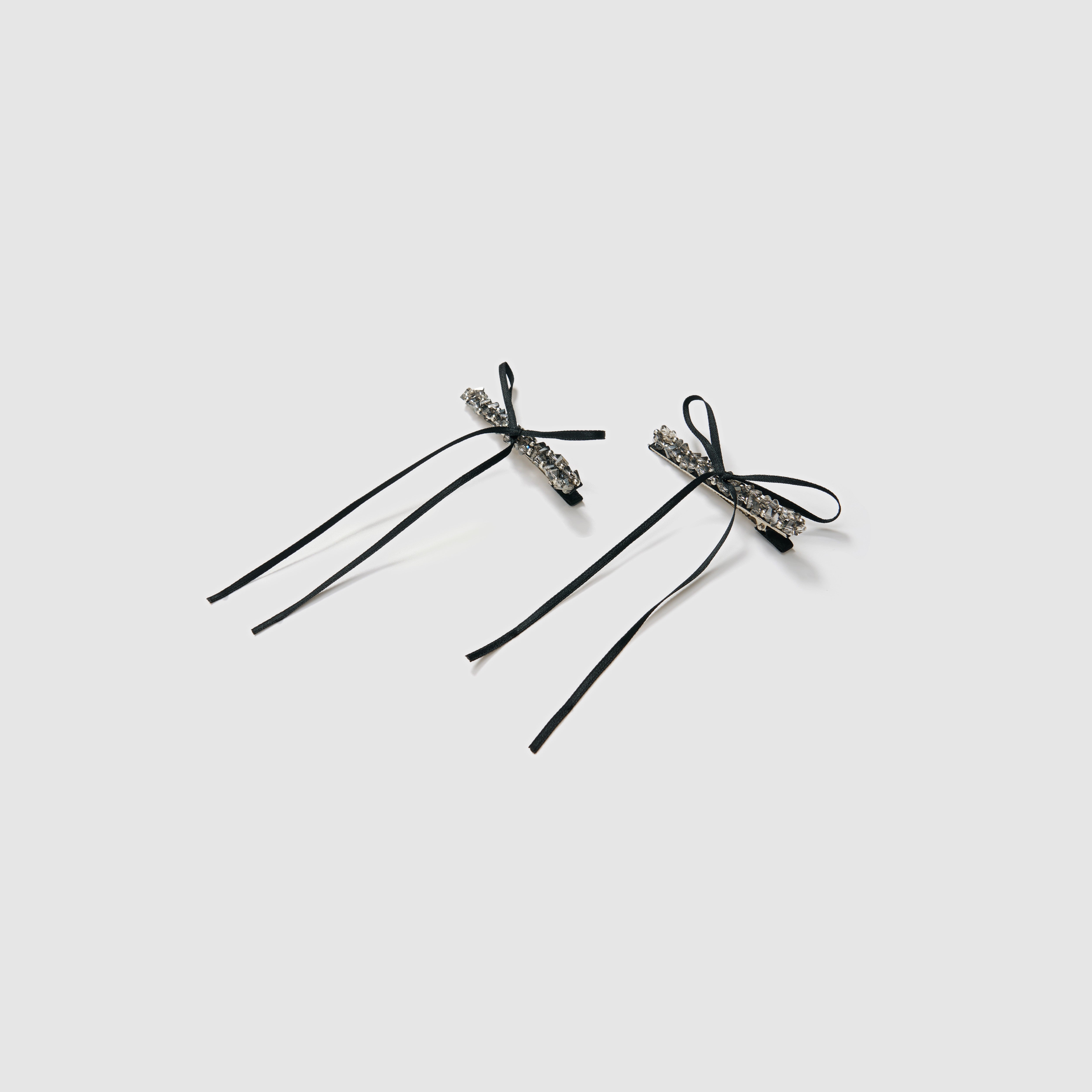 The KIKI and JOJO Girls Black Beaded Bow Hair Clips - Set of 2 features elegant black bows with long ribbon tails and rhinestone accents, displayed on a light gray background—ideal for gifting or adding sparkle to any hairstyle.